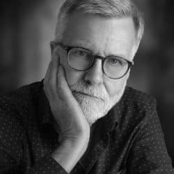 Pensive older man in glasses, black and white photo.