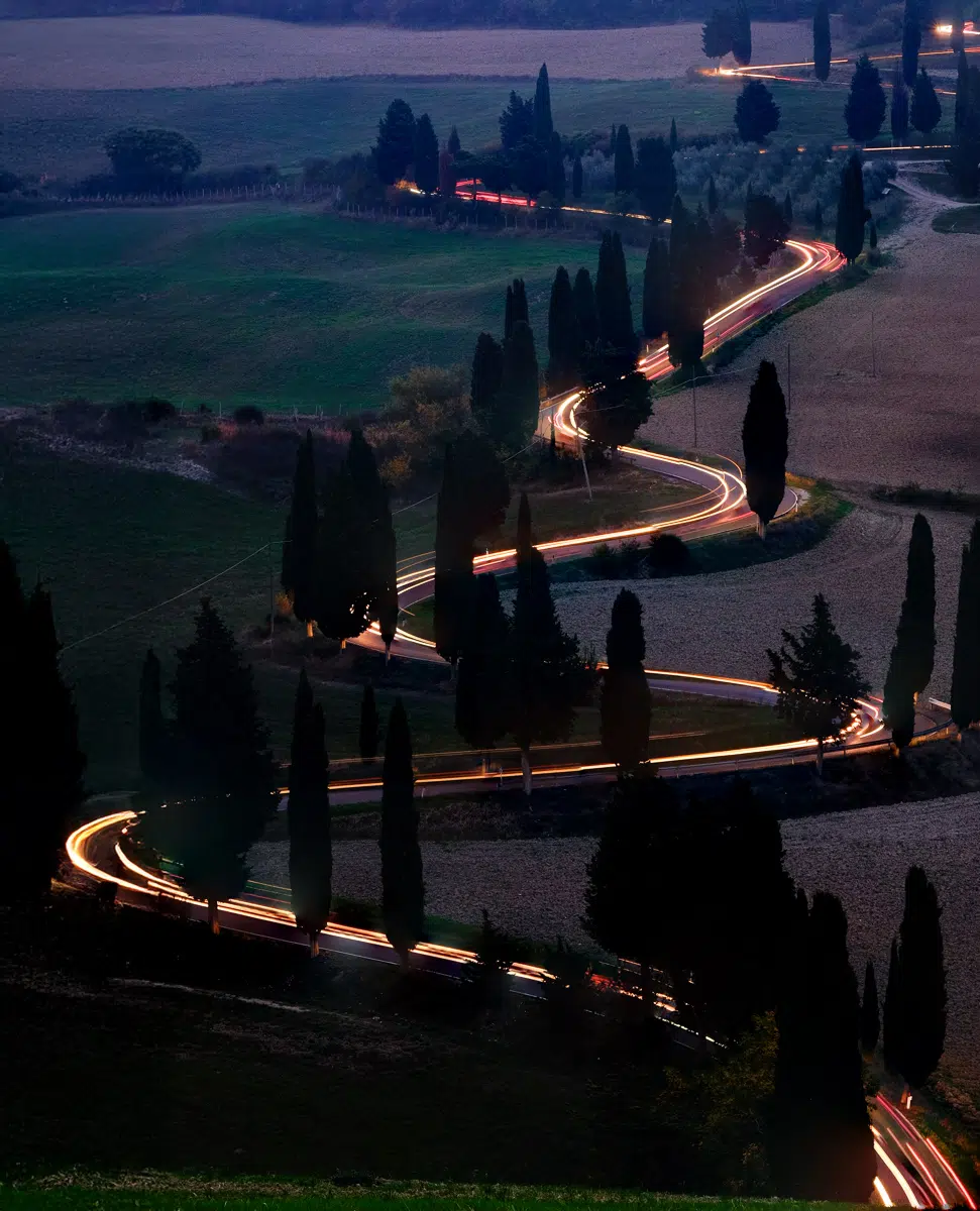 Winding road with car light trails at night