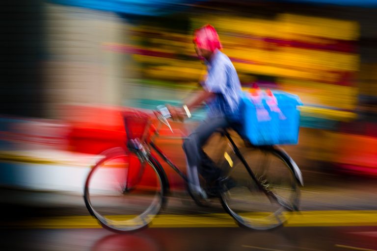 Panning (blurred image) from Singapore of cyclist riding by within a sea oc colour