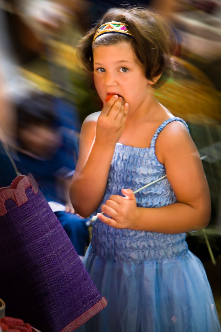 Young girl in blue dress eating strawberry
